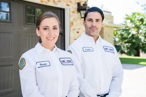 One Hour HVAC Techs Denise and Carlos in front of a Pensacola home's garage